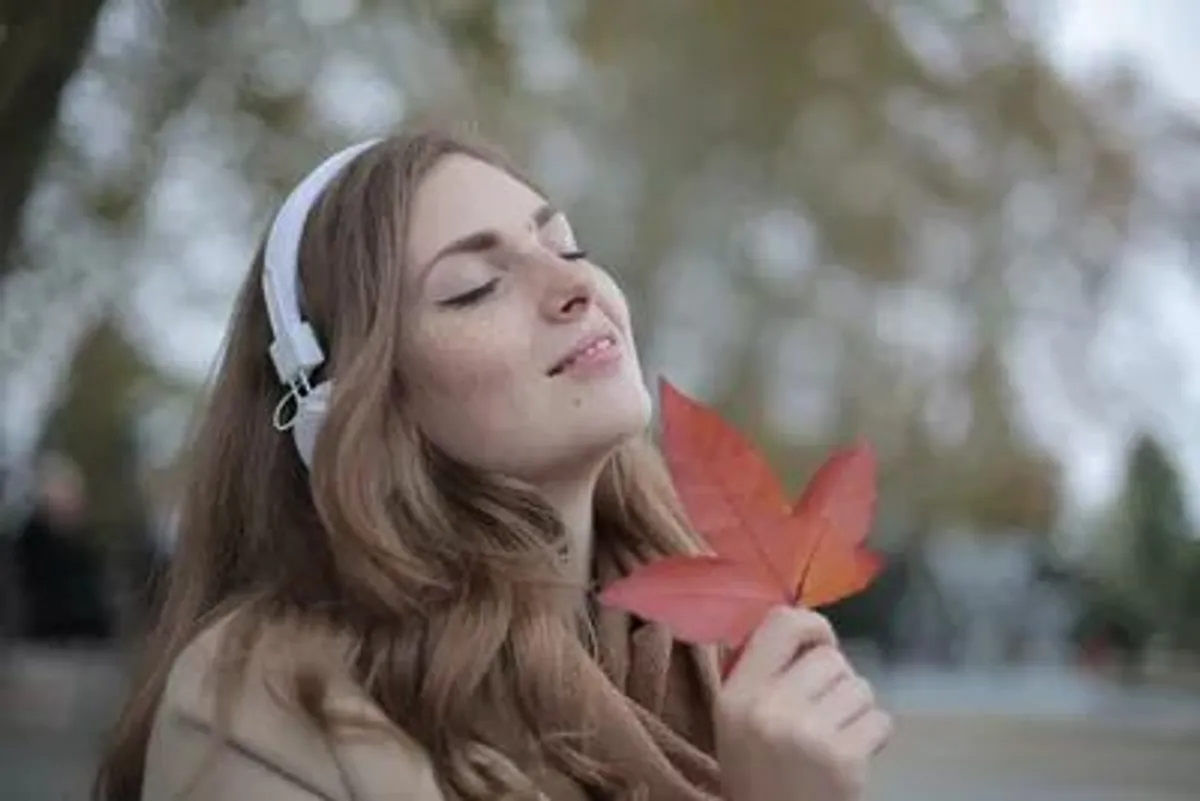 mulher jovem satisfeita ouvindo musica headphones folha vermelha