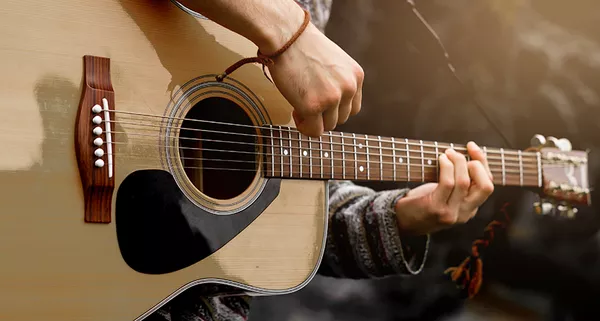 jovem tocando violao acustico