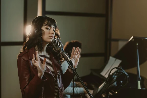 Cantora gravando em estúdio com um músico