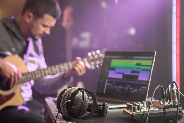 Músico gravando em home studio com um violão