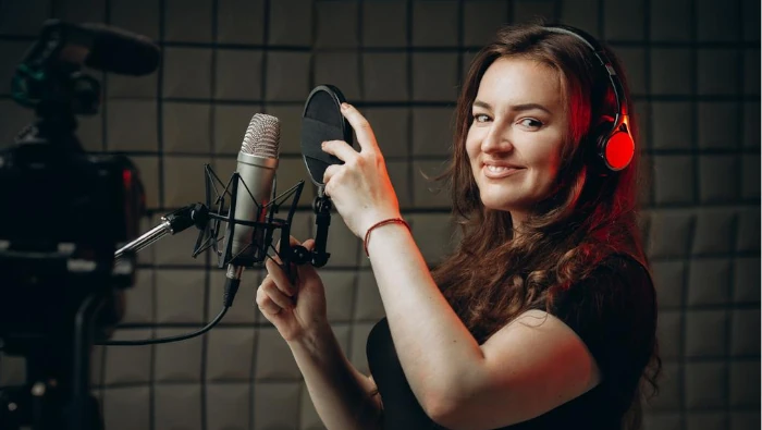 mulher sorridente ajustando um microfone no estúdio
